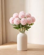Pale Pink artificial pompom chrysanthemums standing in a vase on a pale oak table; no vase is included