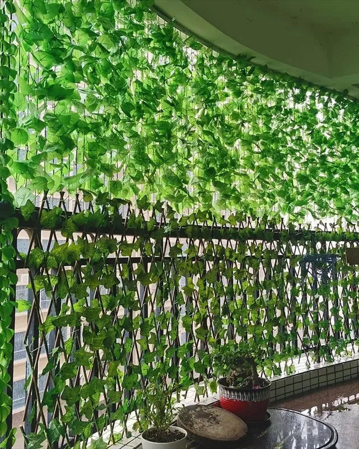 Artificial ivy garland covering a dark wooden garden fence outdoors