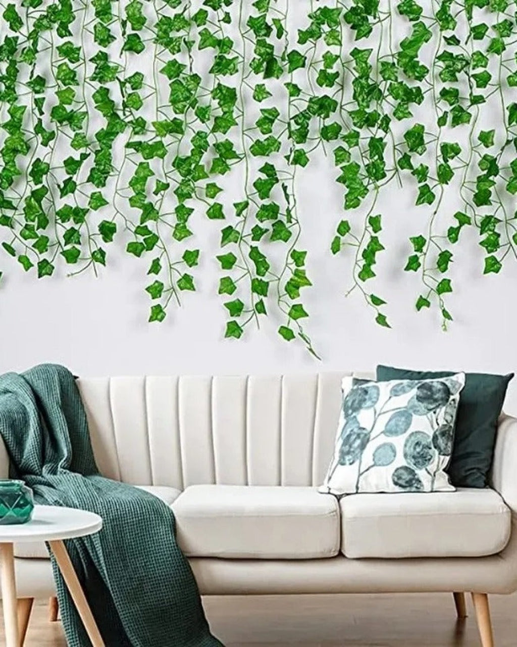 Artificial ivy garland trailing down a living-room wall behind a pale sofa