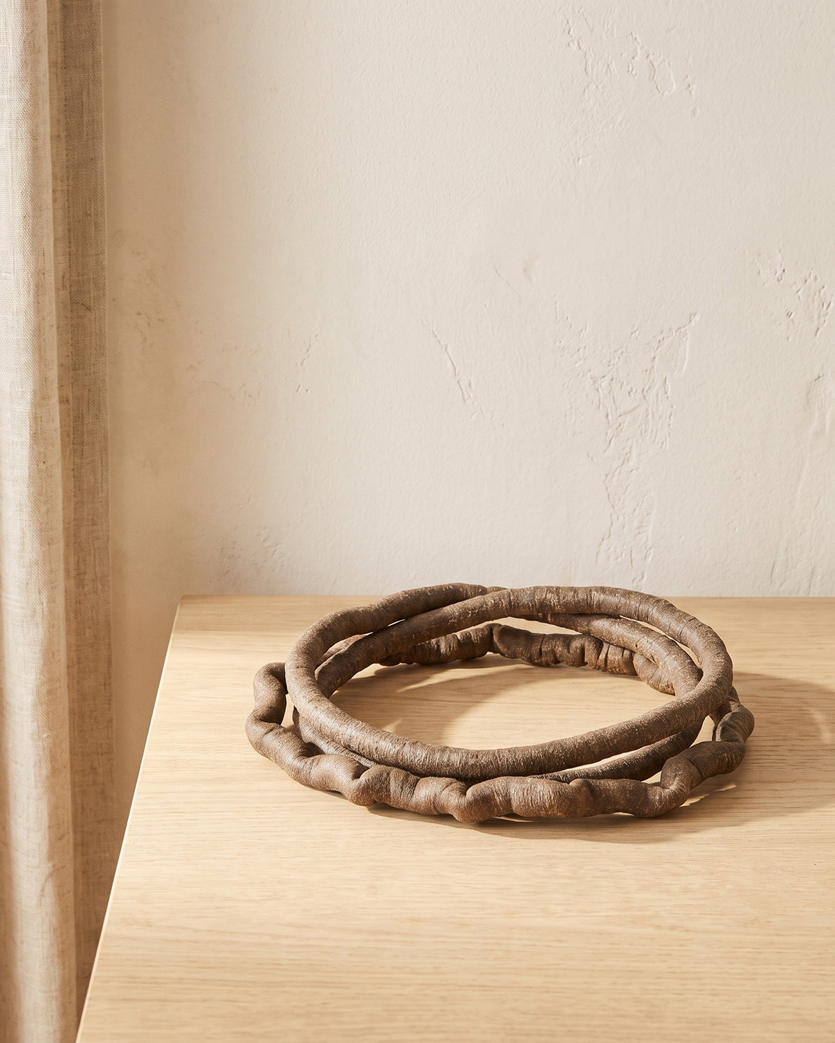 Artificial bark-textured jungle vine coiled on a pale oak table