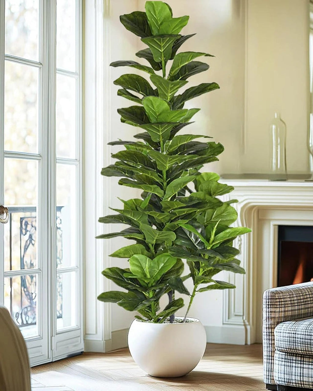 Artificial fiddle leaf fig tree in a white planter beside a fireplace and tall windows