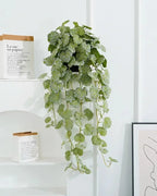 Artificial hanging begonia vine on a white shelf beside a framed print