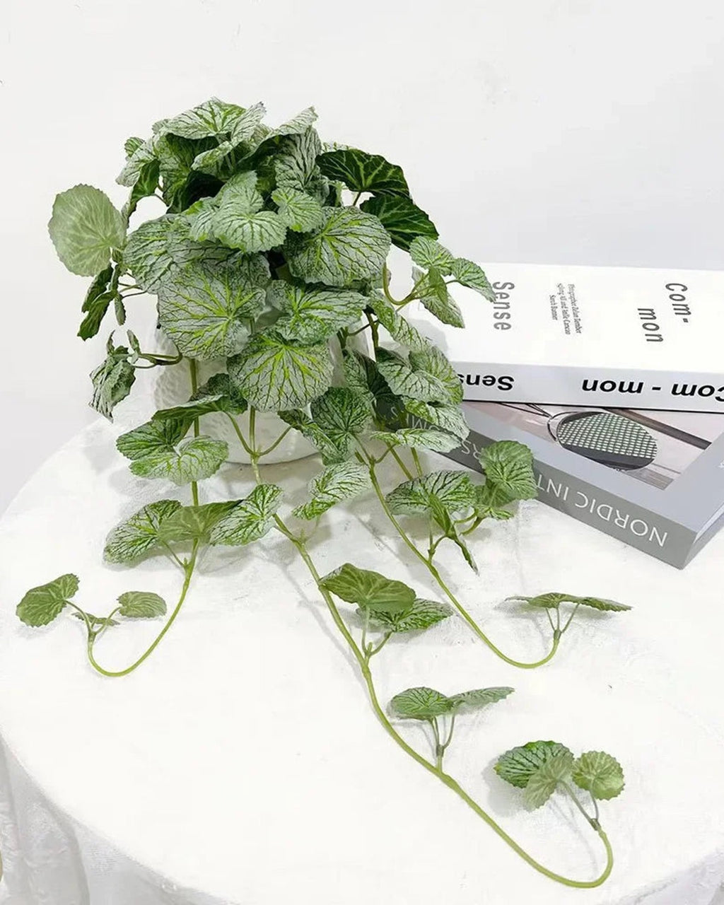 Artificial begonia vine on a white table with its trailing stems spread out