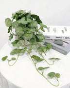 Artificial begonia vine on a white table with its trailing stems spread out
