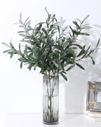 Artificial olive branches in a ribbed glass vase, side view