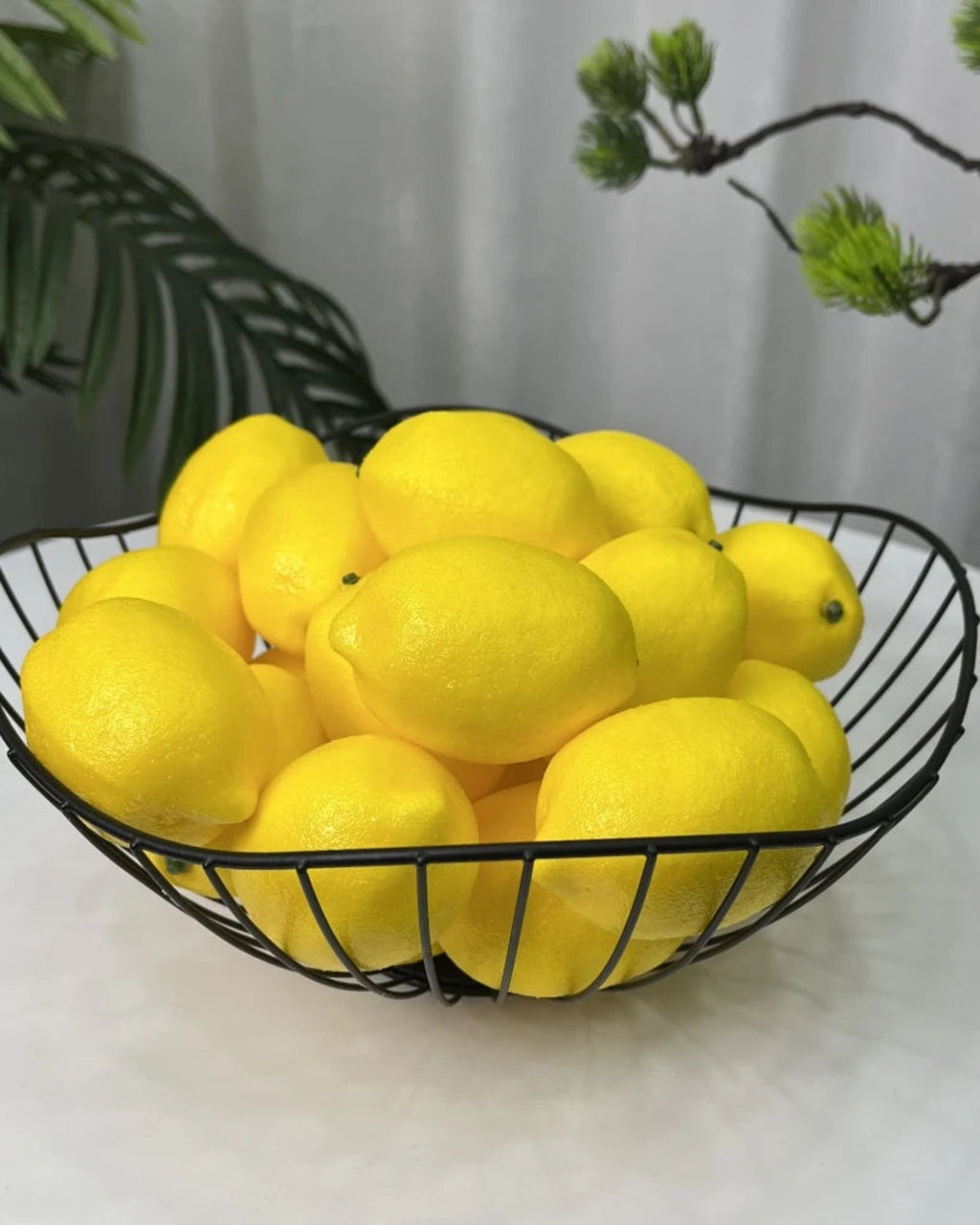 Artificial lemons piled in a black wire bowl