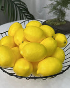 Artificial lemons in a black wire bowl on a table