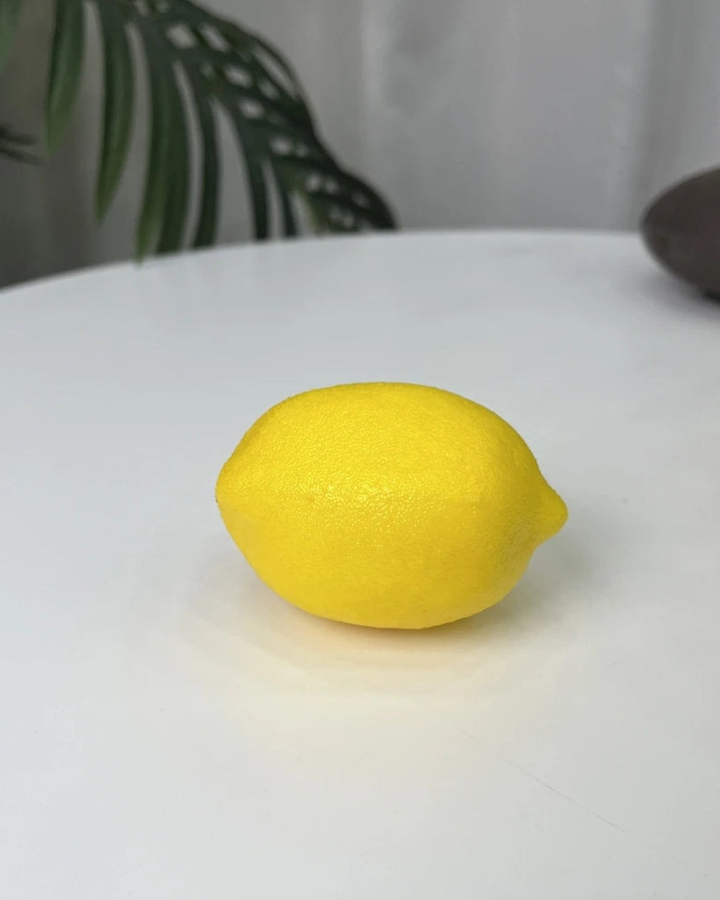 A single artificial lemon on a plain white surface