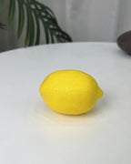 A single artificial lemon on a plain white surface