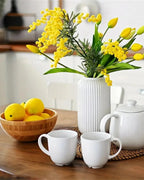 Artificial lemons in a wooden bowl beside a vase of flowers; only the lemons are part of the order