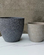 Two stone effect plant pots on marble against a concrete wall; plants not included