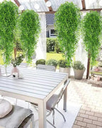 Green artificial wisteria sprays hung in a row from a pergola over a garden table; each order is one spray