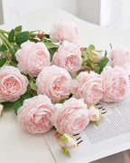 Pink artificial rose branches laid on an open book; each order is one branch