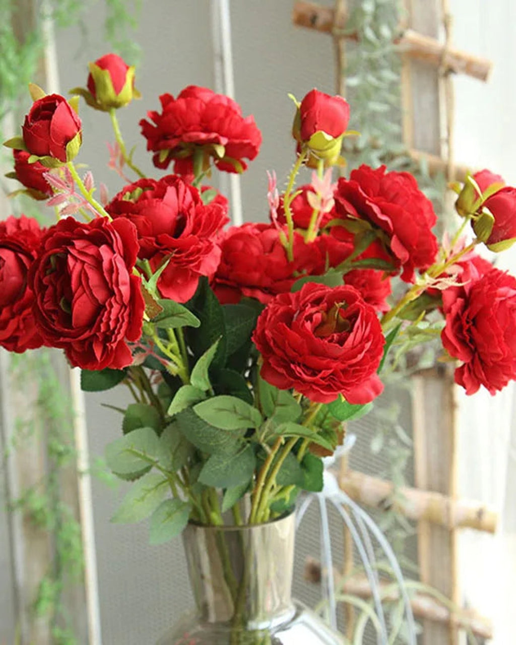 Red artificial rose branches in a metal jug outdoors; each order is one branch, and no vase is included