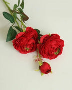 Red, artificial rose branch: two open blooms and a bud on one stem