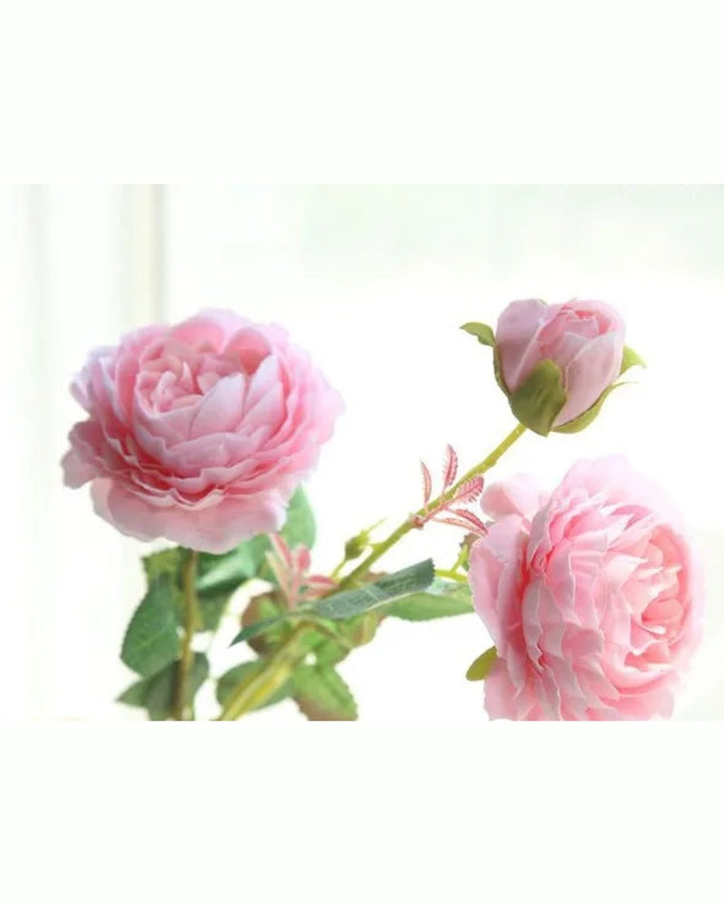 Pink, artificial rose branch: two open blooms and a bud on one stem