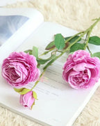 Purple, artificial rose branch: two open blooms and a bud on one stem