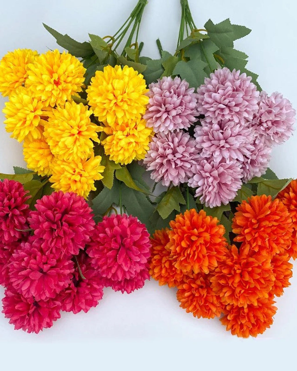 Six of the colors of artificial pompom chrysanthemums laid together; fourteen colors are offered
