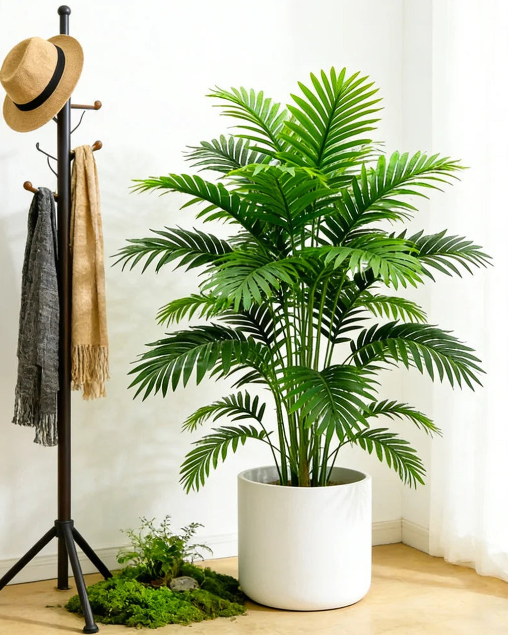 An artificial palm leaf bush beside a coat stand in a hallway; pot not included