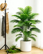 An artificial palm leaf bush beside a coat stand in a hallway; pot not included