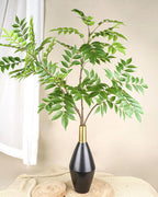 An artificial tree branch standing in a dark vase on a table; no vase is included