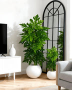 An artificial papaya leaf plant beside a media cabinet; the smaller plant next to it is not part of the order, and no pot is included