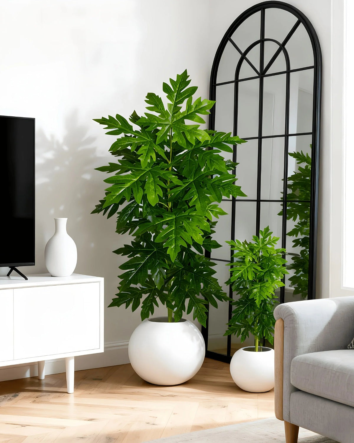 An artificial papaya leaf plant beside a media cabinet; the smaller plant next to it is not part of the order, and no pot is included