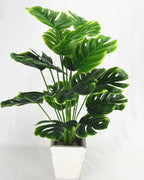 An artificial monstera plant in a plain white pot, its split leaves spread wide; pot not included