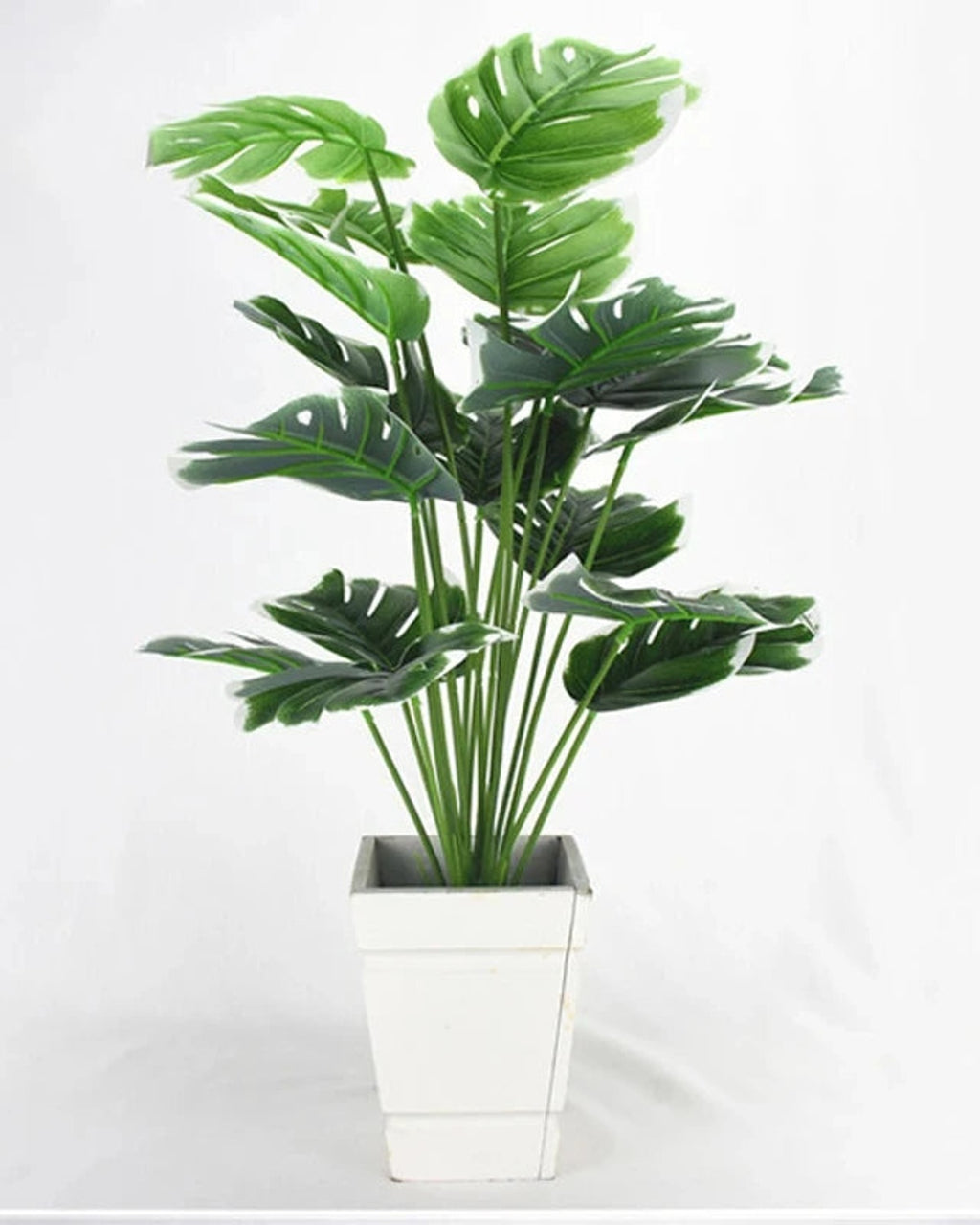 An artificial monstera plant in a plain white pot, seen from the front; pot not included