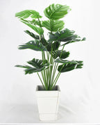 An artificial monstera plant in a plain white pot, seen from the front; pot not included