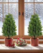 Two artificial mini Christmas trees in pots on a windowsill with snow outside; each order is two trees, and no pot is included