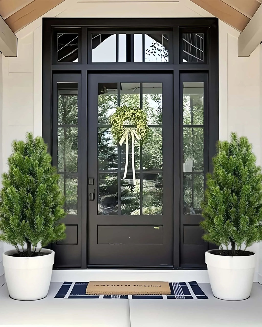 Two artificial mini Christmas trees in pots either side of a front door; each order is two trees, and no pot is included