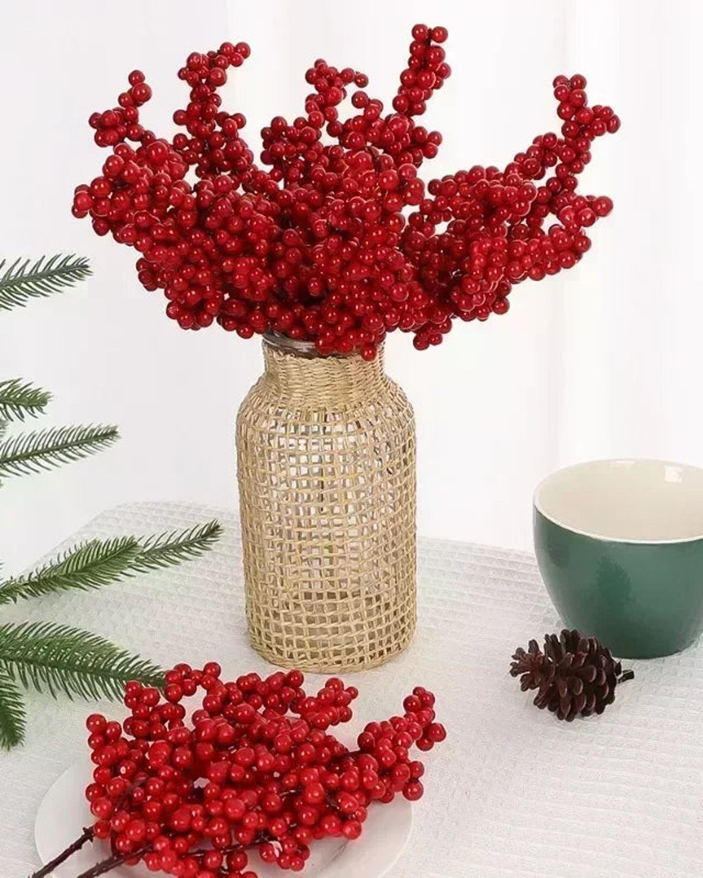 Artificial berry branches in a woven vase with more laid beside it; no vase is included