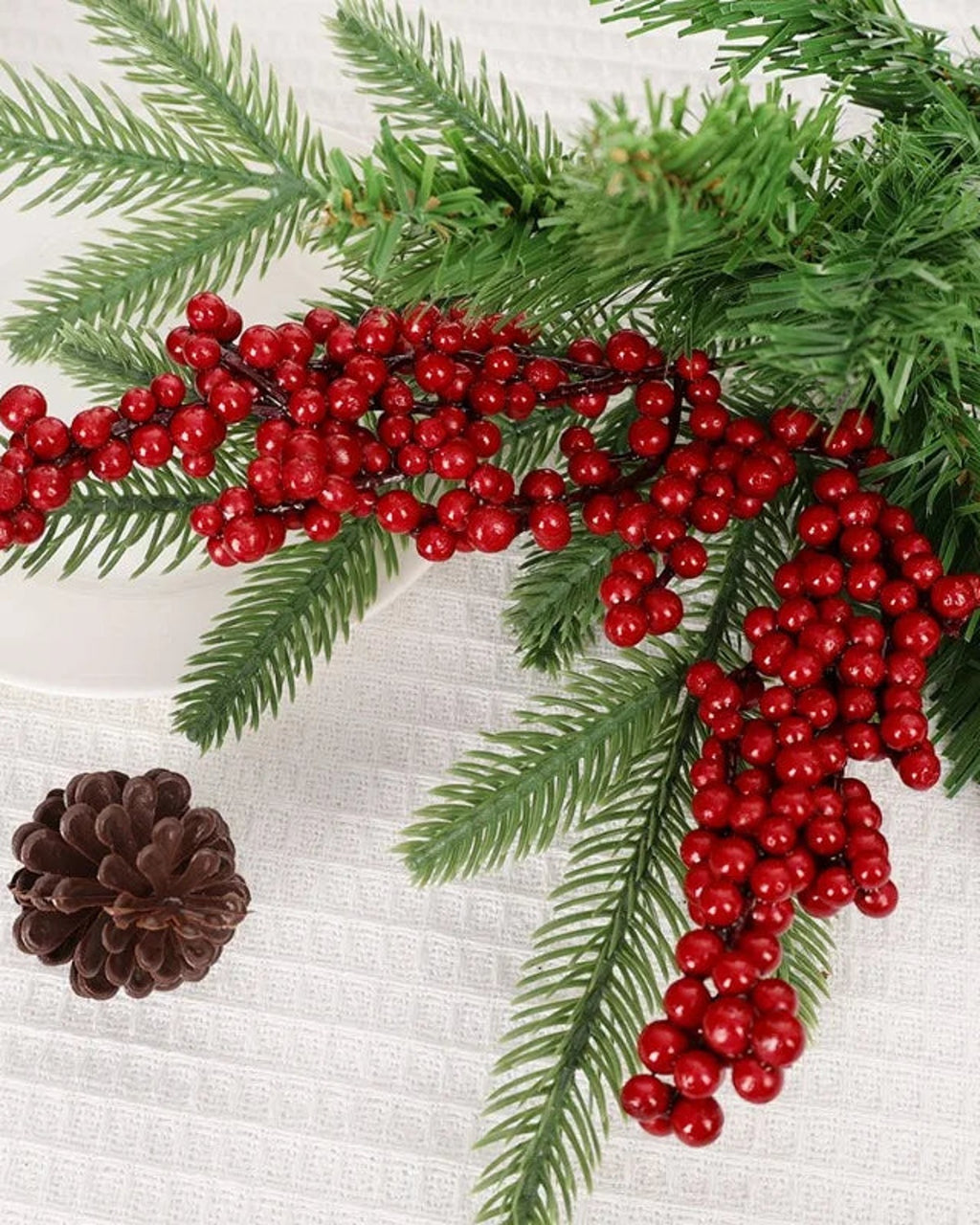 Artificial berry branches beside fir foliage and a pine cone; only the berry branches are part of the order