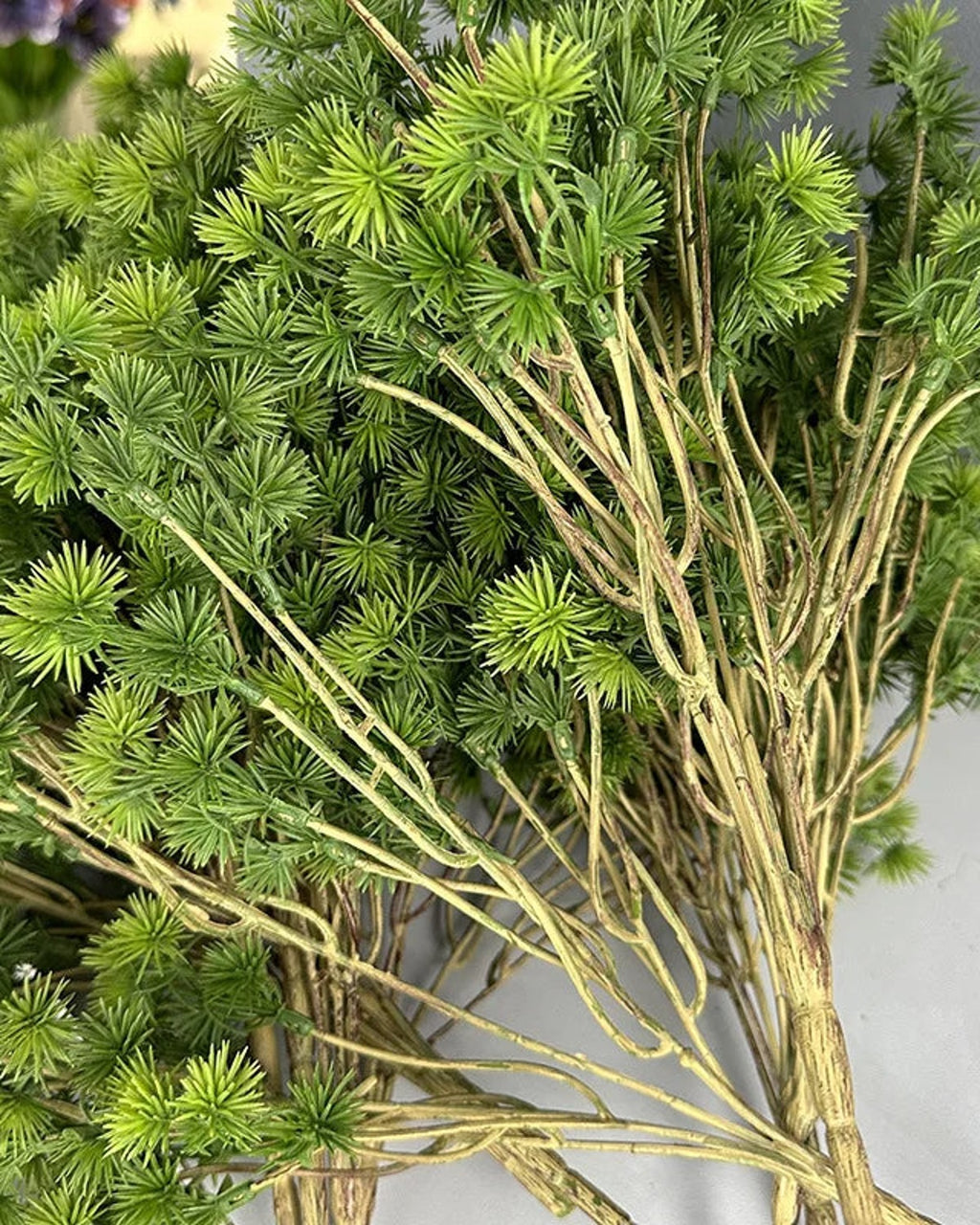 The needle tufts and bare wired twigs of the artificial pine branch in close view