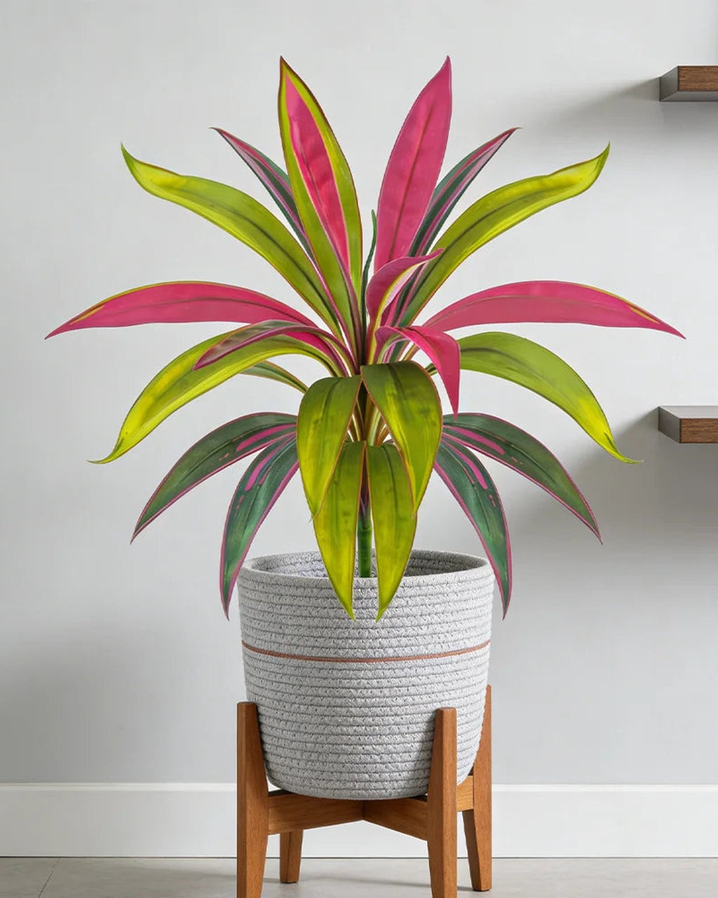 The pink artificial dracaena in a ribbed pot on a wooden stand; pot not included