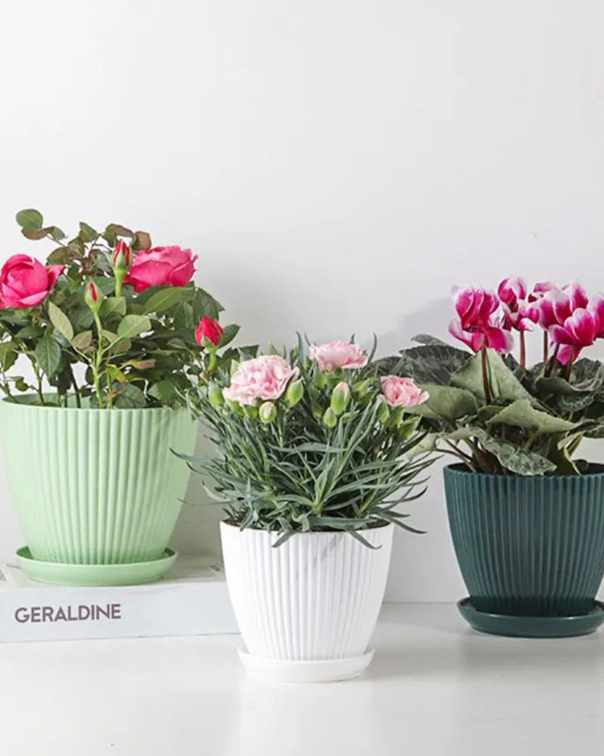 Mint, white and forest green fluted plant pots holding flowers; flowers not included