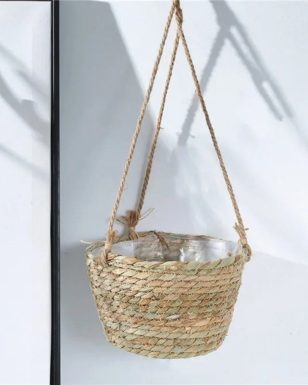 A woven hanging plant basket hanging beside a framed print