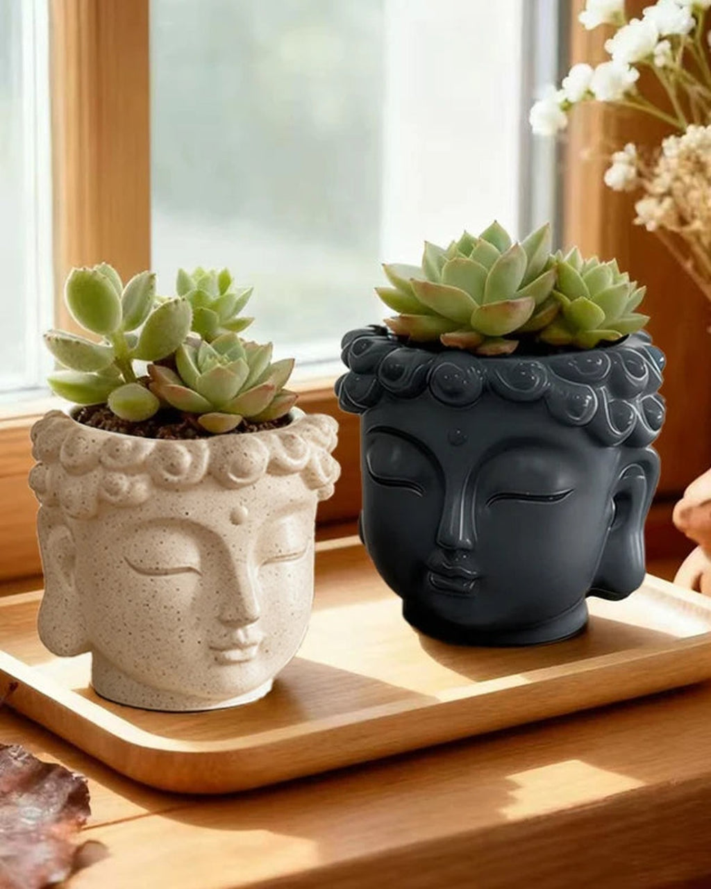 Stone and charcoal Buddha head planters on a wooden tray with succulents; plants not included