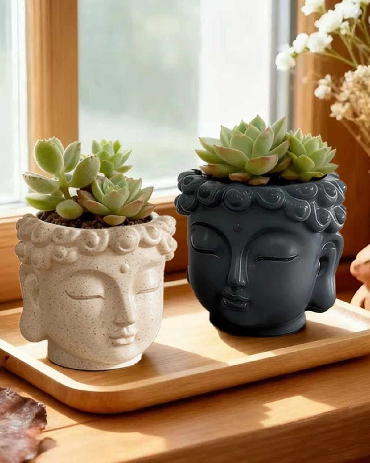 Stone and charcoal Buddha head planters on a wooden tray with succulents; plants not included