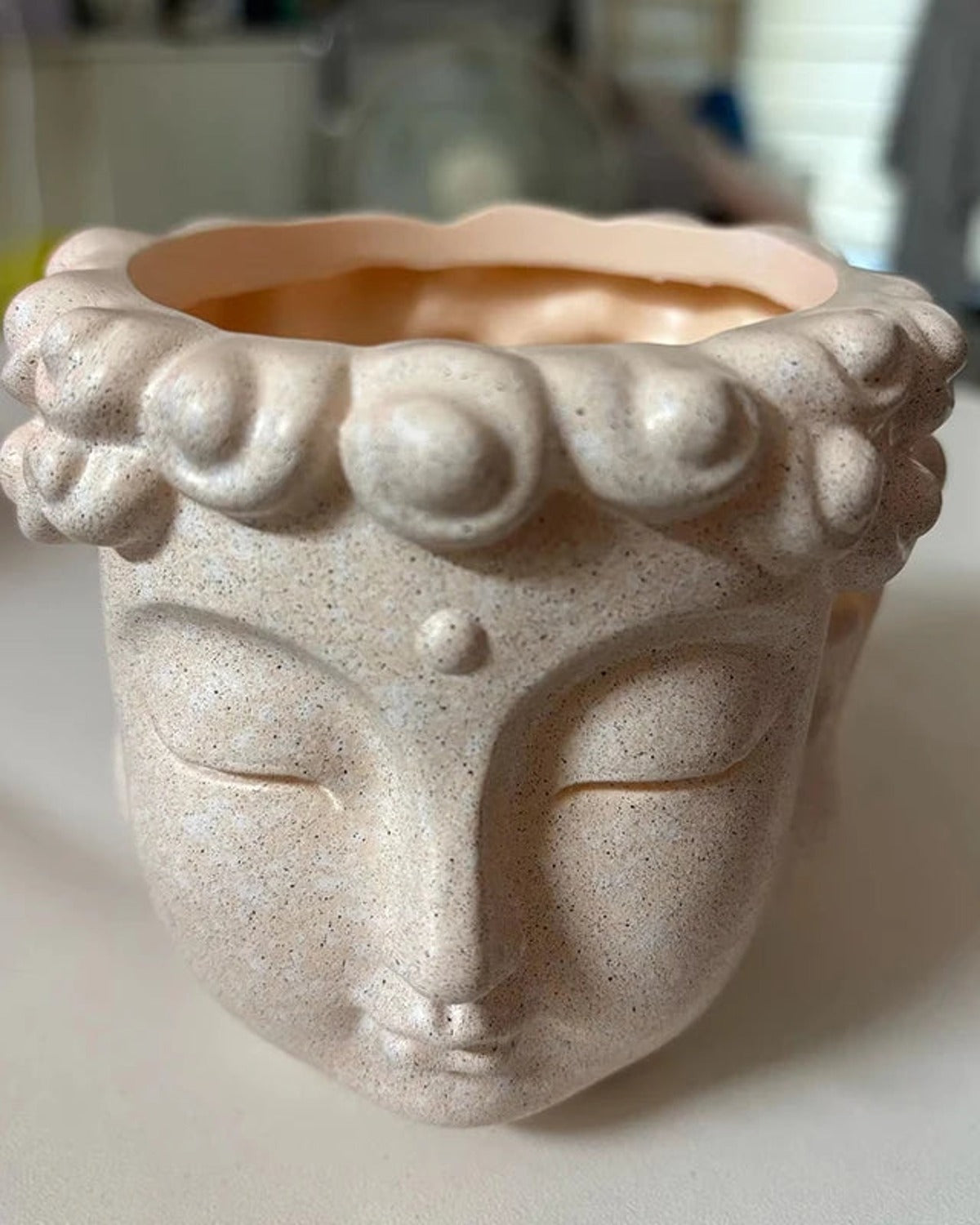 A close look at the speckled stone finish and the raised curls of the Buddha head planter