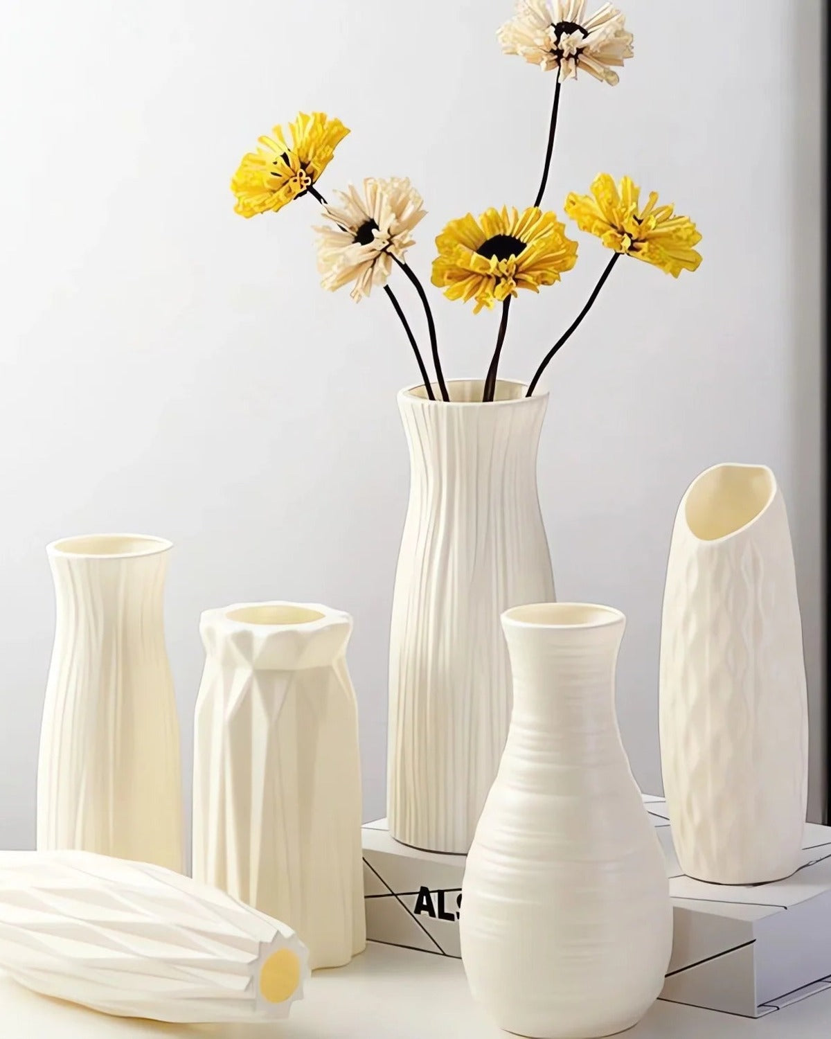 Five white origami vases grouped on a table with dried flowers; flowers not included