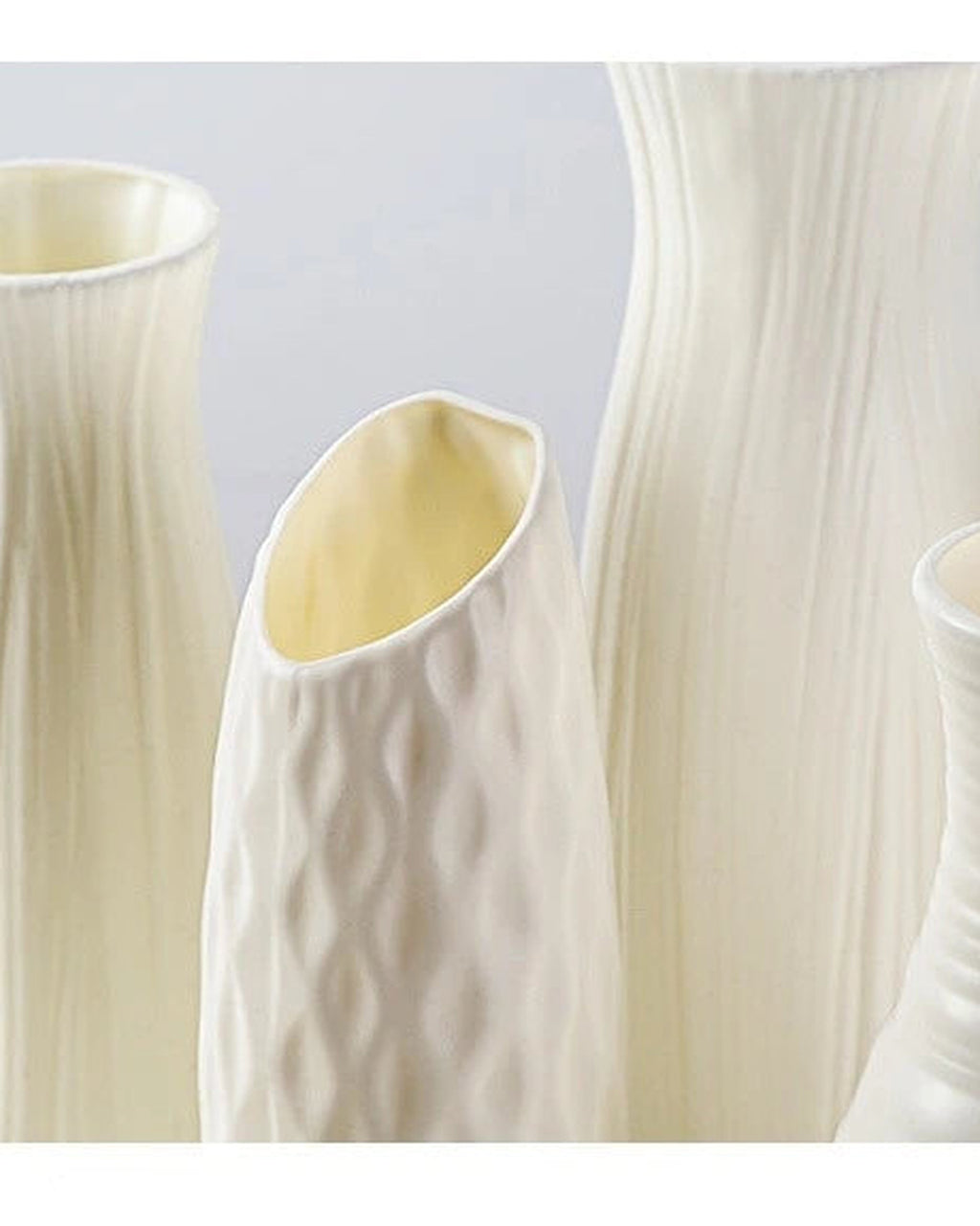 Four of the white origami vase shapes side by side, empty