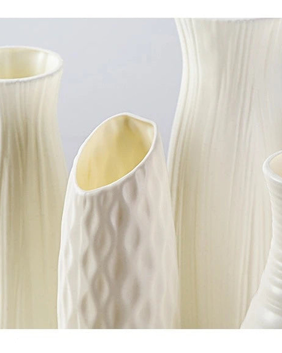 Four of the white origami vase shapes side by side, empty