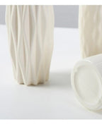 Two white origami vases, one on its side, showing the mouth and the wall thickness