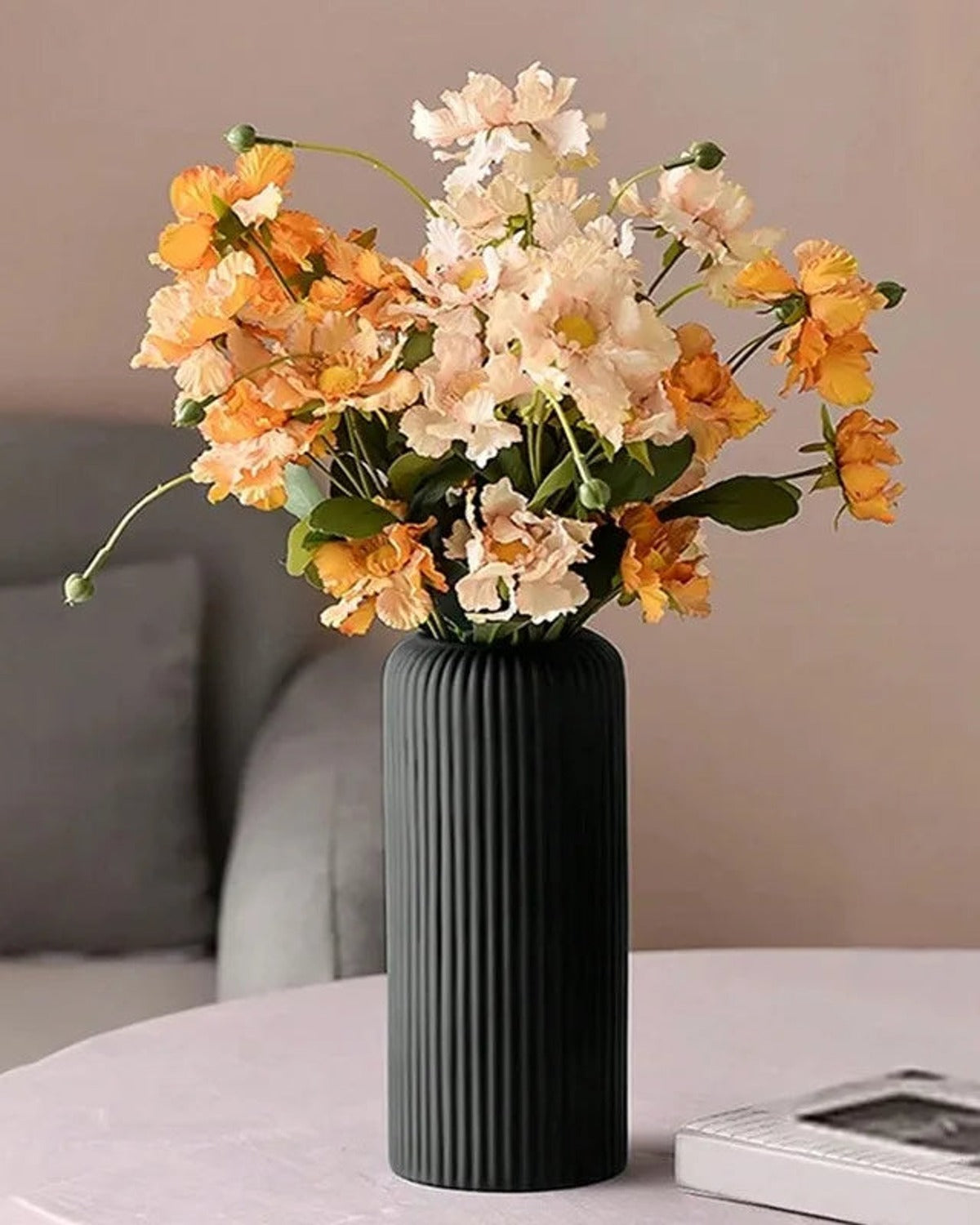 A black striped cylinder vase holding orange blossom on a bedside table; flowers not included