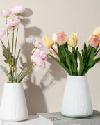 Two fluted tapered vases holding tulips and ranunculus; flowers not included