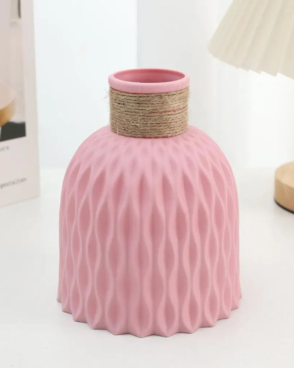 A pink rope neck vase beside a white one on a desk under a lamp; lamp not included