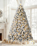 A pre-lit snow flocked Christmas tree lit beside a fireplace; wreath and gifts not included