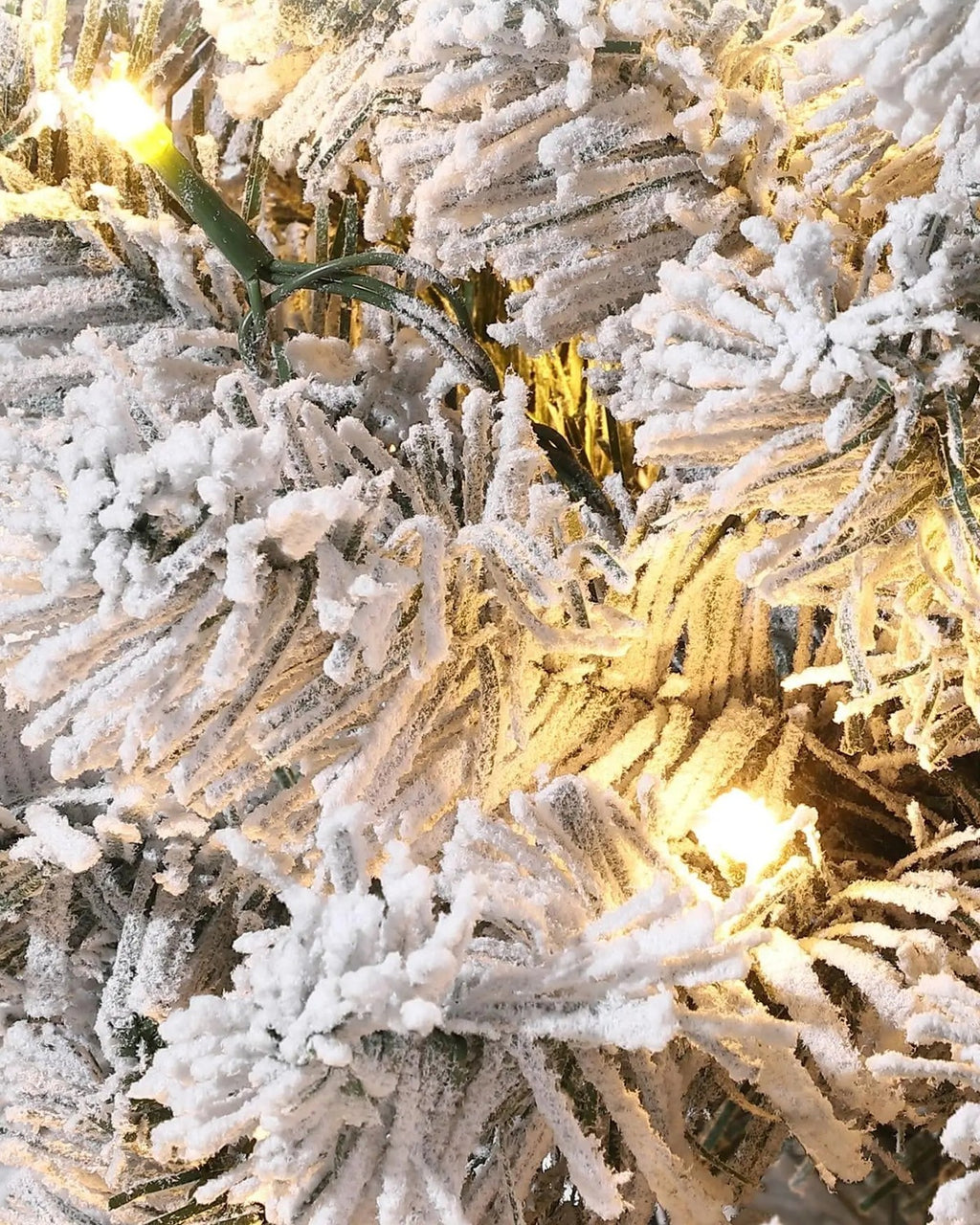 A close look at the pre-lit tree's snow flocked branch tips with their warm white lights on
